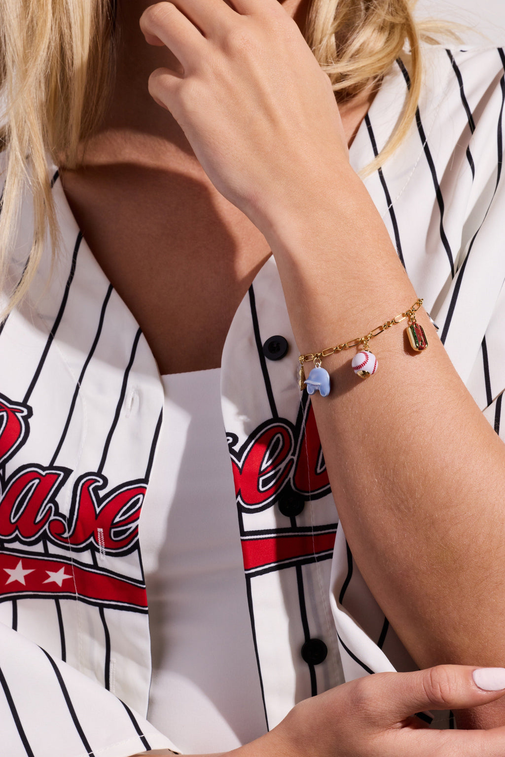 Two-tone baseball charm bracelet on wrist with blue glove and baseball charms visible