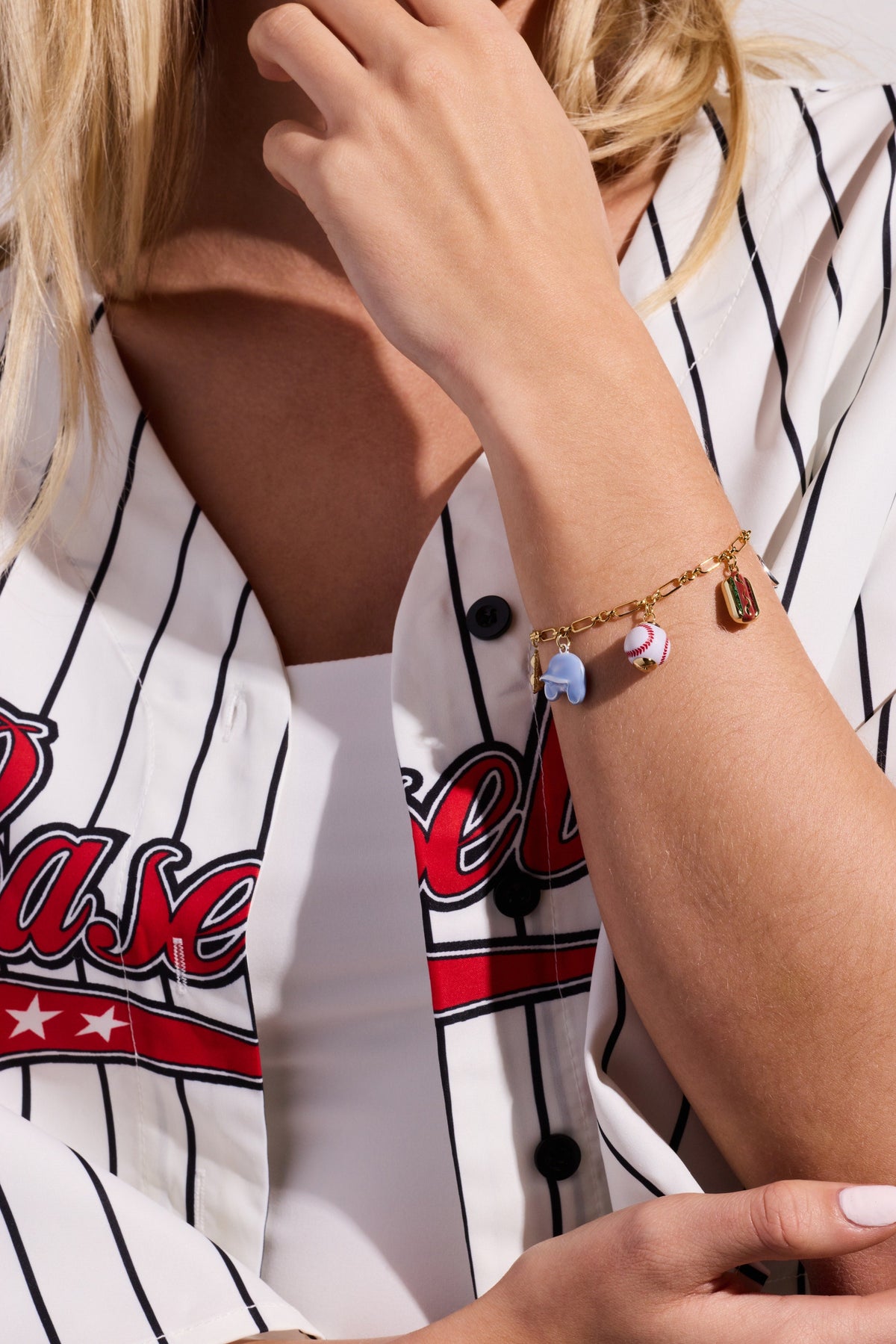Two-tone baseball charm bracelet on wrist with blue glove and baseball charms visible