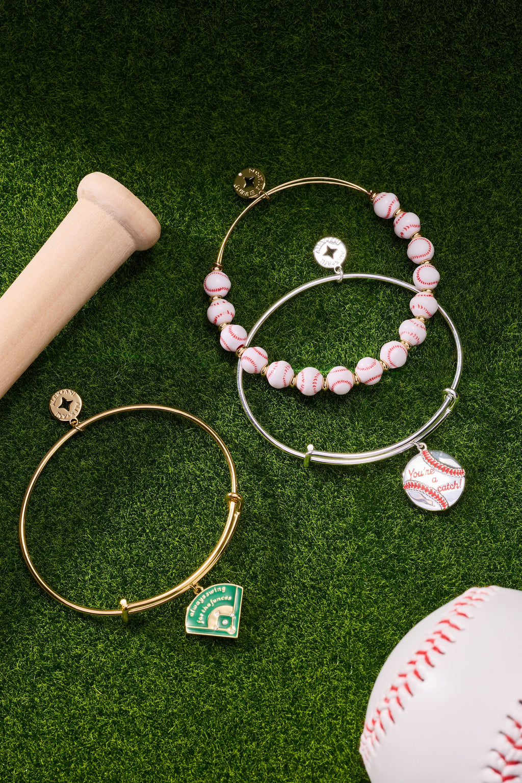 Gold-tone bangles with pink bead accents and green baseball diamond charm