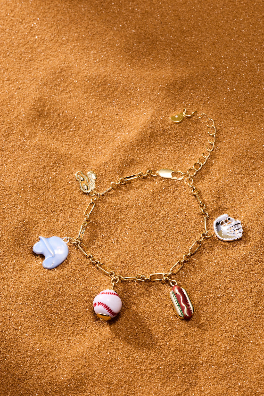 Two-tone baseball charm bracelet with blue glove, baseball, and hot dog charms on sand