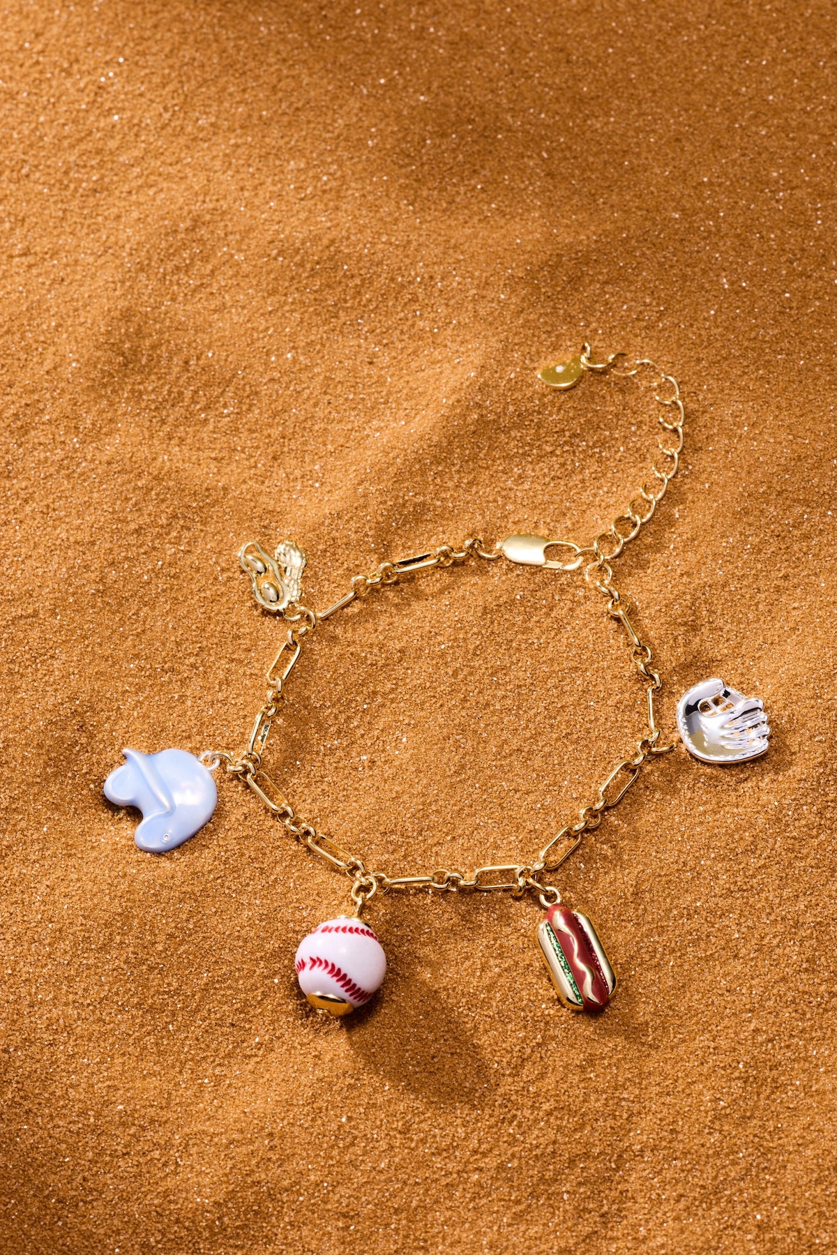 Two-tone baseball charm bracelet with blue glove, baseball, and hot dog charms on sand