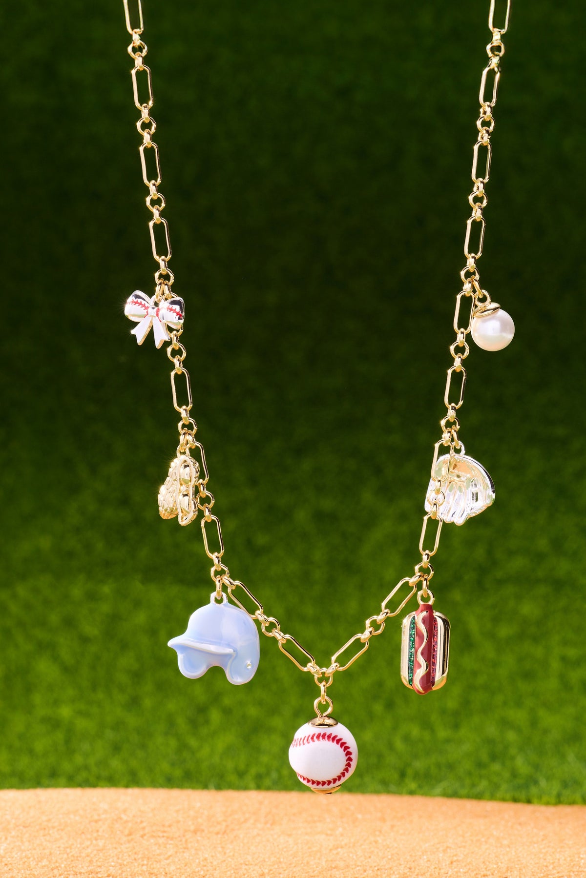 Gold two-tone multi-charm necklace with baseball charm, pearl, hot dog and heart bow