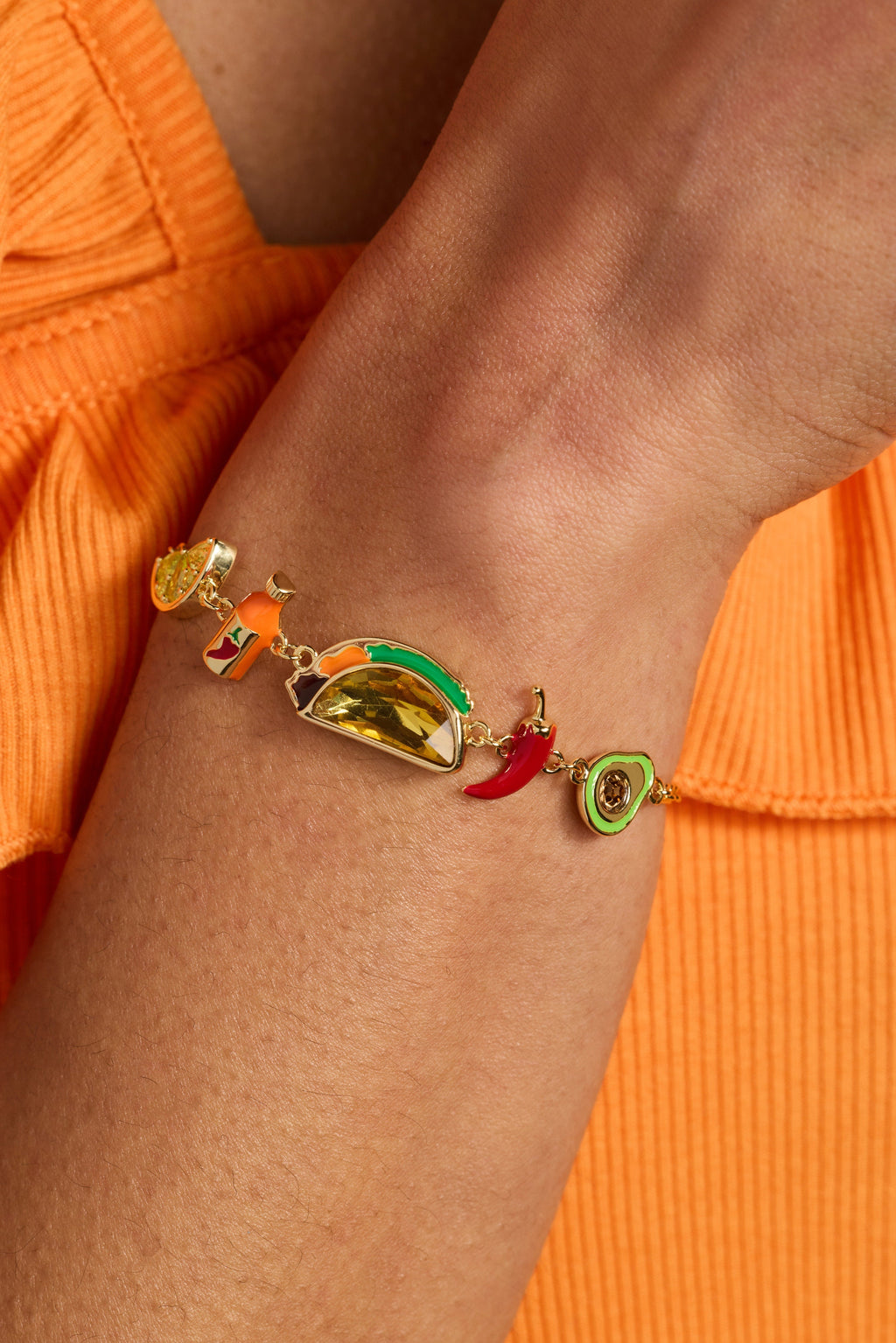 Gold-tone taco charm bracelet on wrist with red chili and green citrus charms