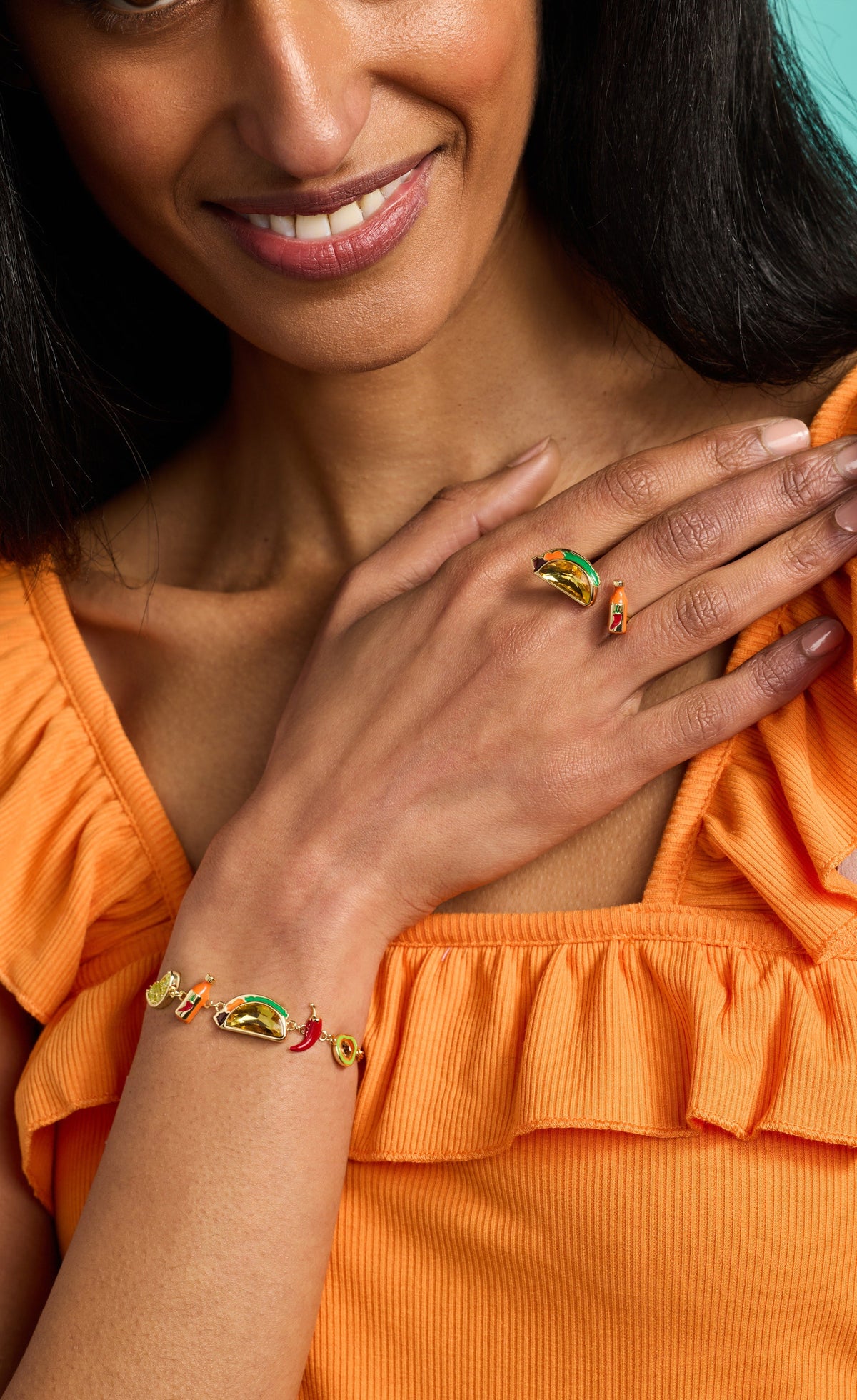 Gold-tone taco charm bracelet on wrist with red chili and green citrus charms