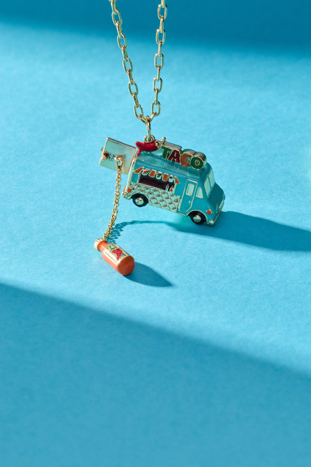 Gold taco truck locket necklace with taco truck pendant and chili bottle charm.