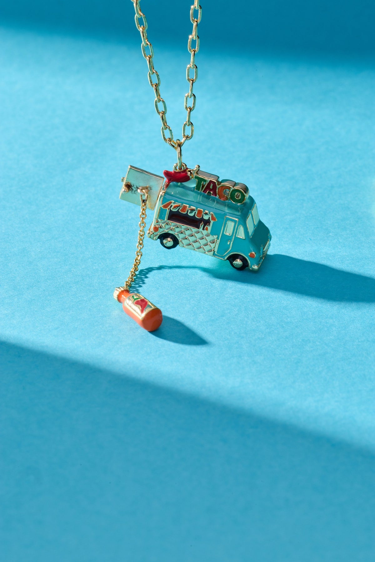 Gold taco truck locket necklace with taco truck pendant and chili bottle charm.