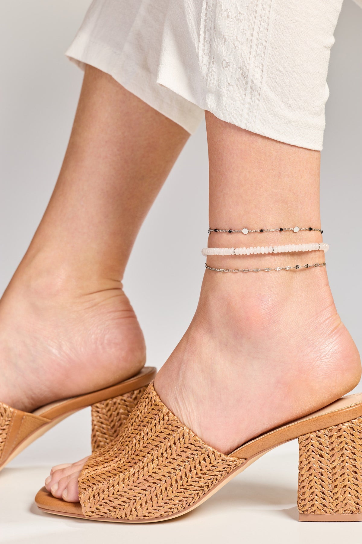 Rose-tone chain anklet set with small faceted links on an ankle