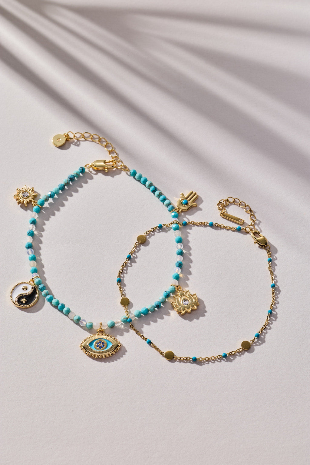 Turquoise bead anklet with gold charms, including evil eye and yin-yang
