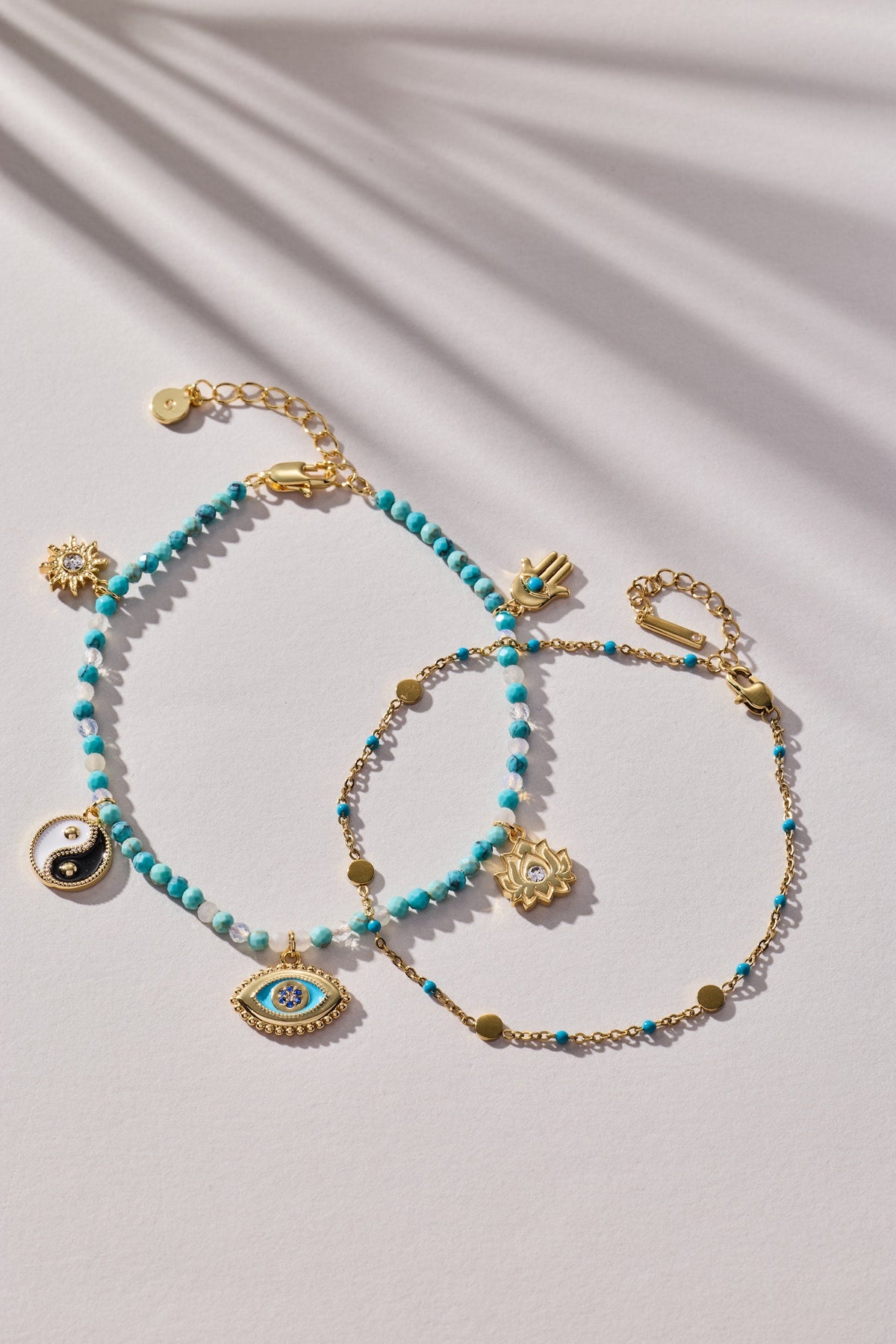 Turquoise bead anklet with gold charms, including evil eye and yin-yang