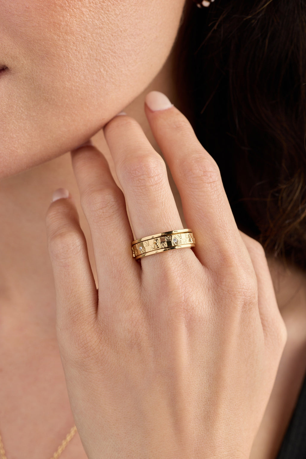 Gold-tone chess fidget ring close-up on hand, engraved band with small stones