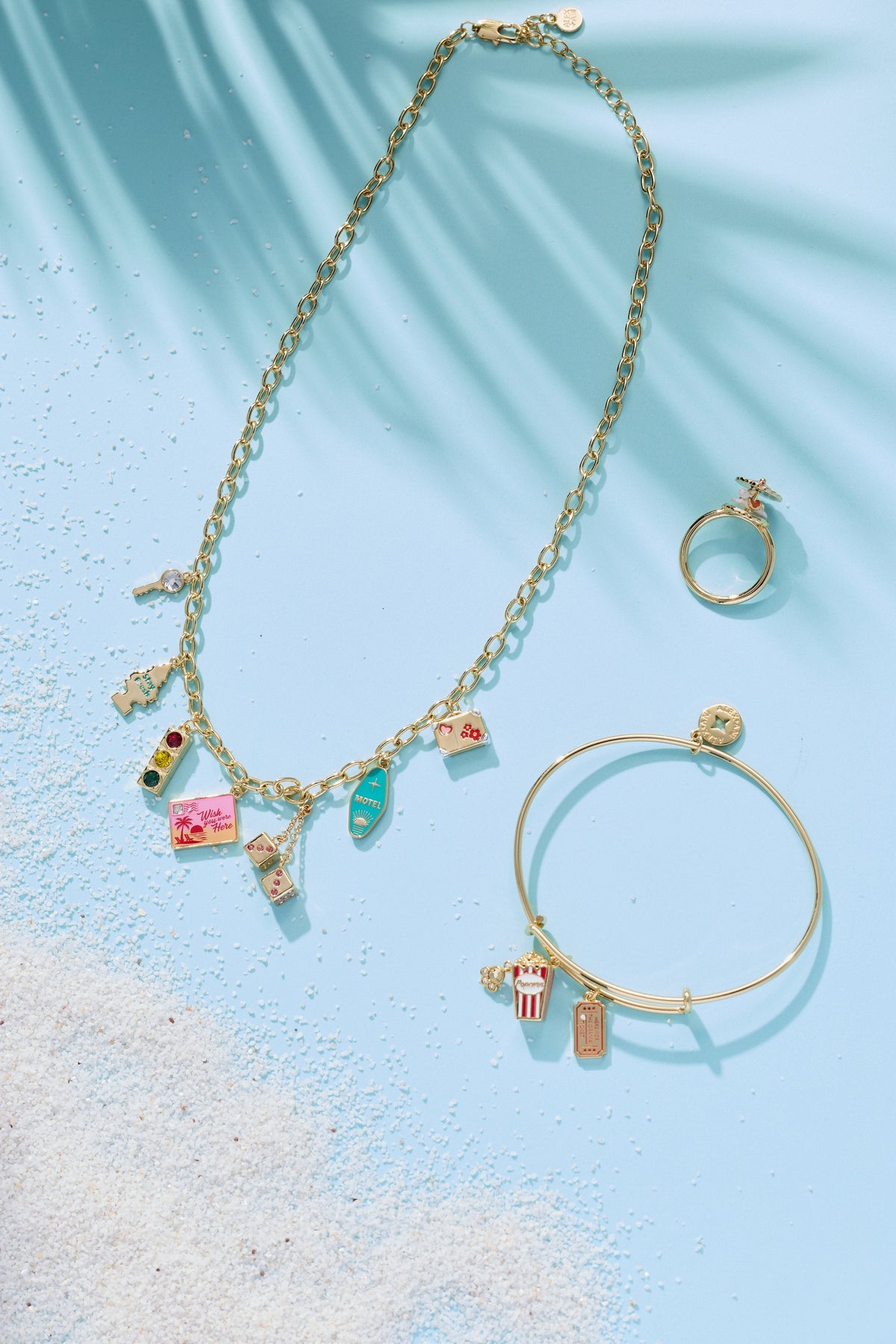 Gold multi-charm necklace with dangling travel charms, plus matching charm bracelet