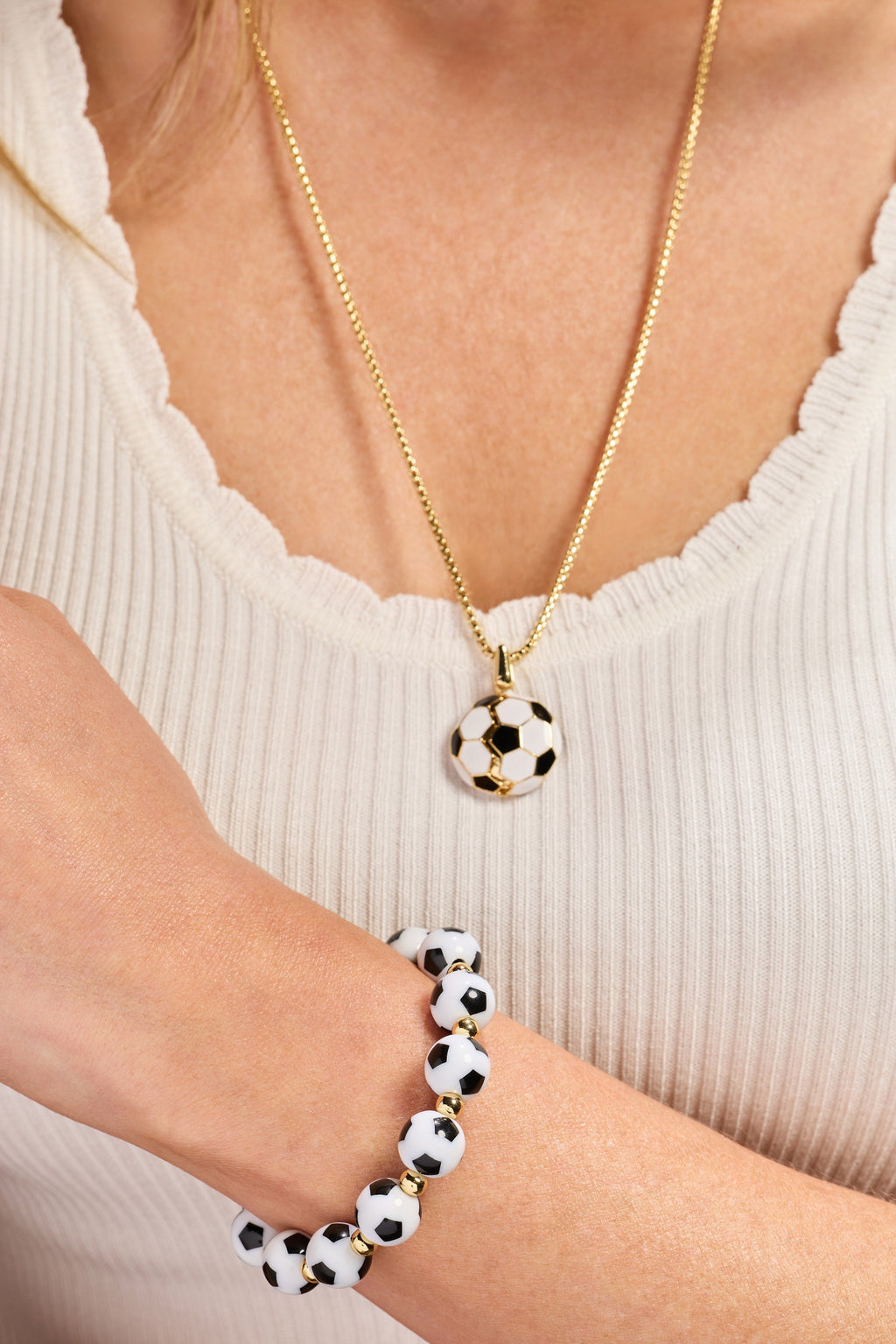 Gold soccer ball locket necklace on chest with soccer ball pendant and matching bracelet