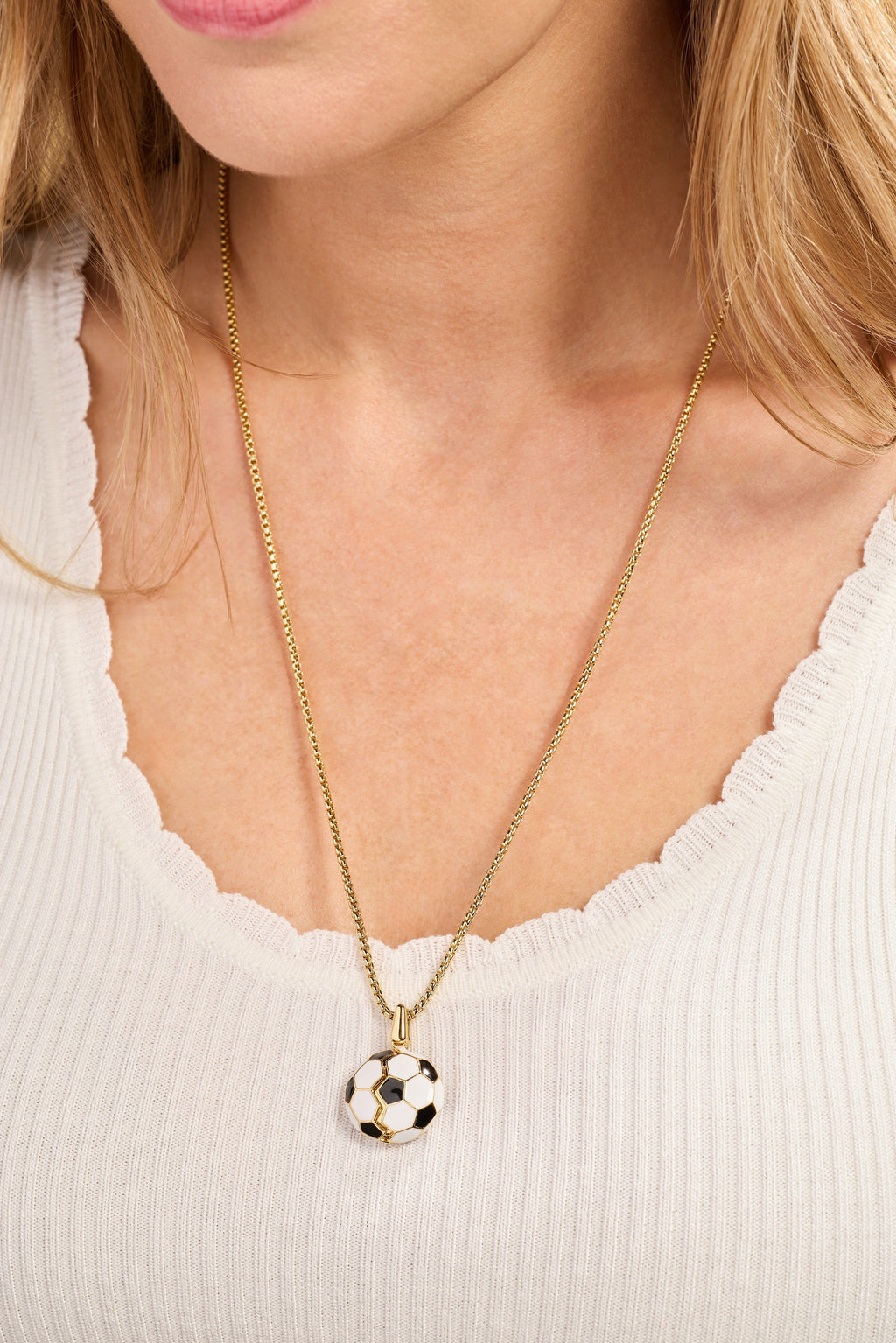 Gold soccer ball locket necklace worn with small soccer ball pendant at collar