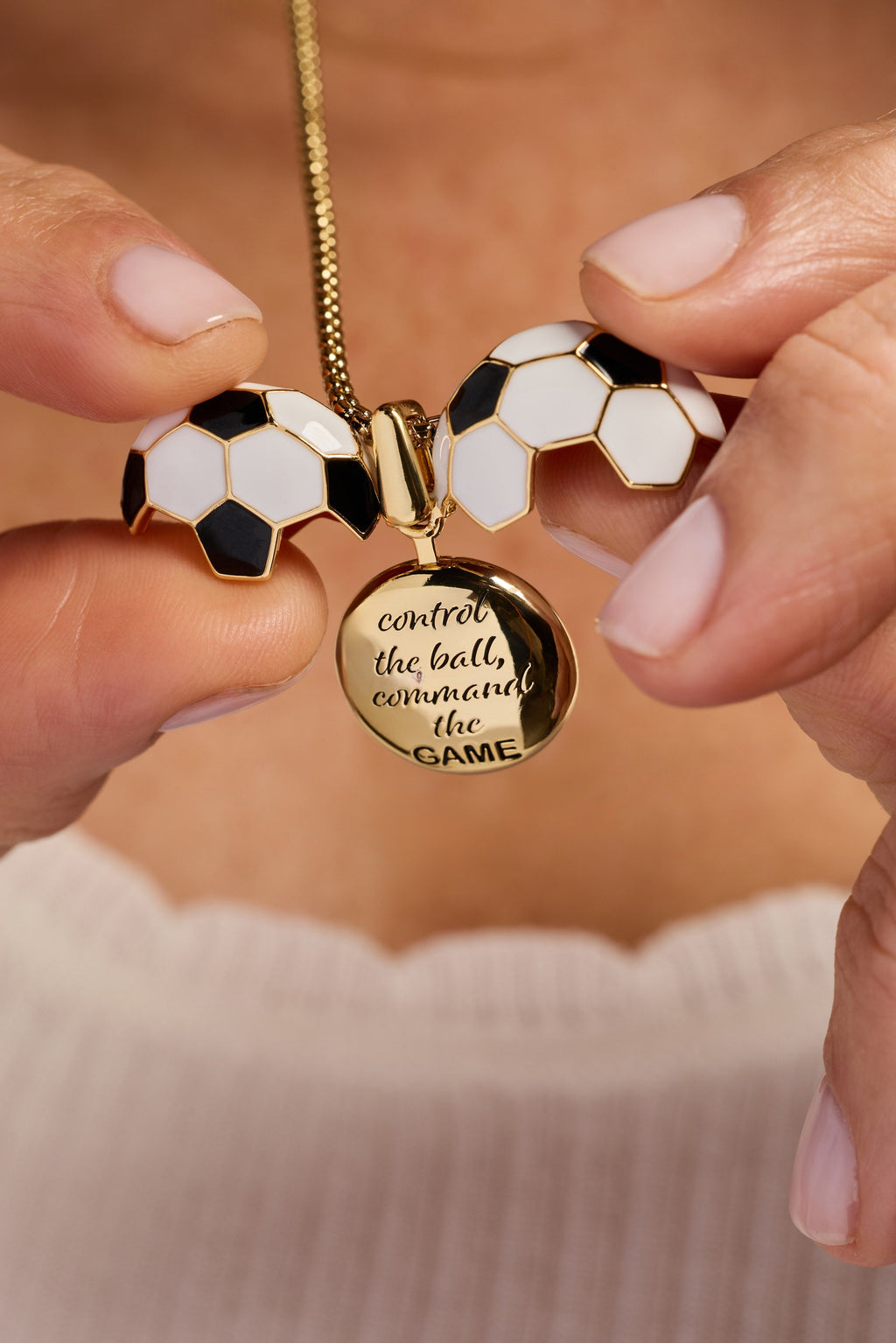 Gold soccer ball locket necklace with round locket text and soccer ball charms held by hands