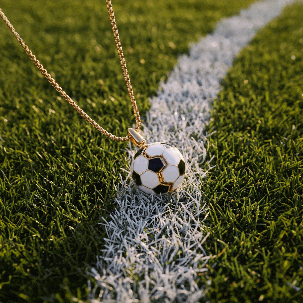 Gold soccer ball locket necklace resting on grass with soccer ball pendant and chain