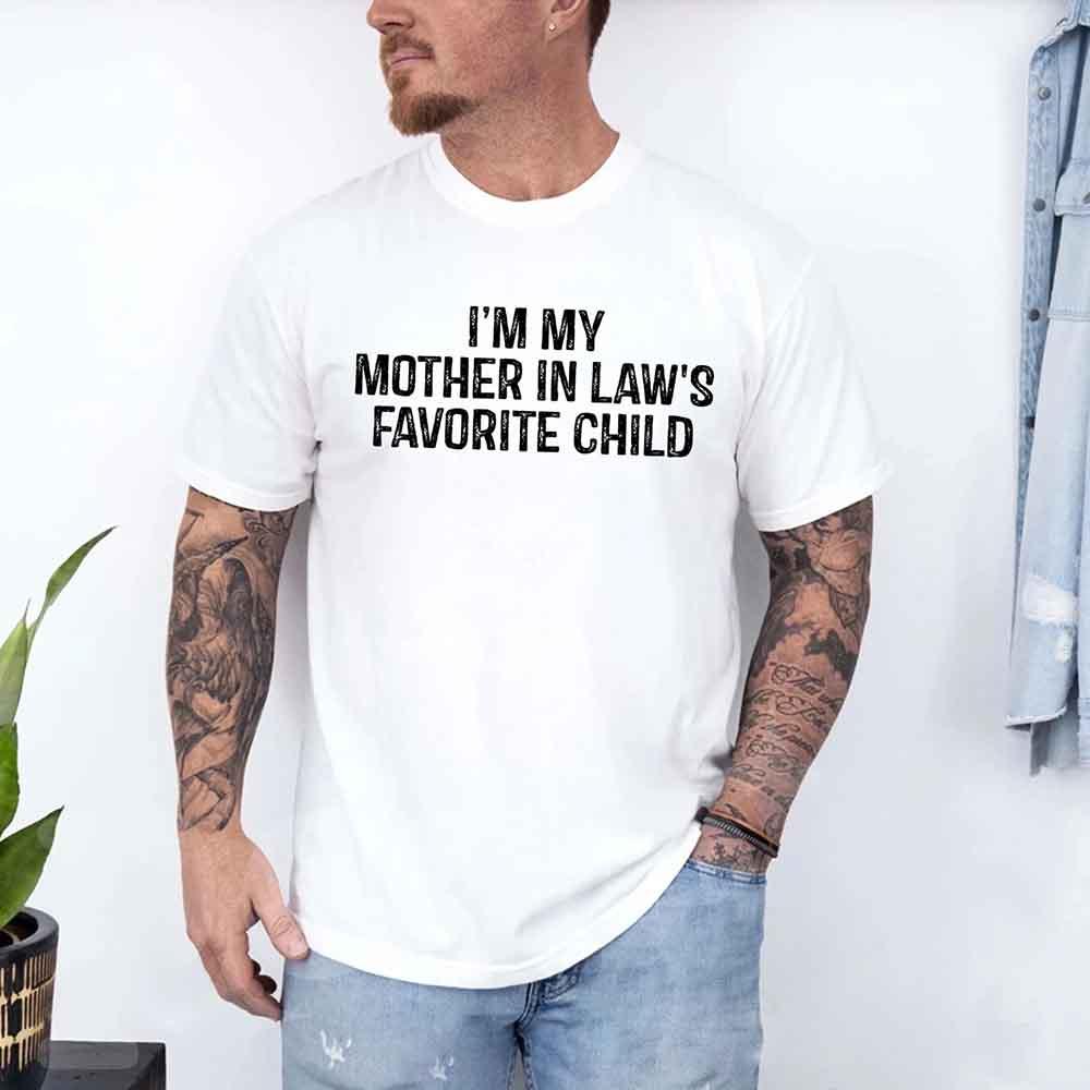 White crew-neck T-shirt worn by a man; reads “I’M MY MOTHER IN LAW’S FAVORITE CHILD”.
