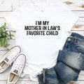 White crew-neck T-shirt with bold text “I’M MY MOTHER IN LAW’S FAVORITE CHILD”.