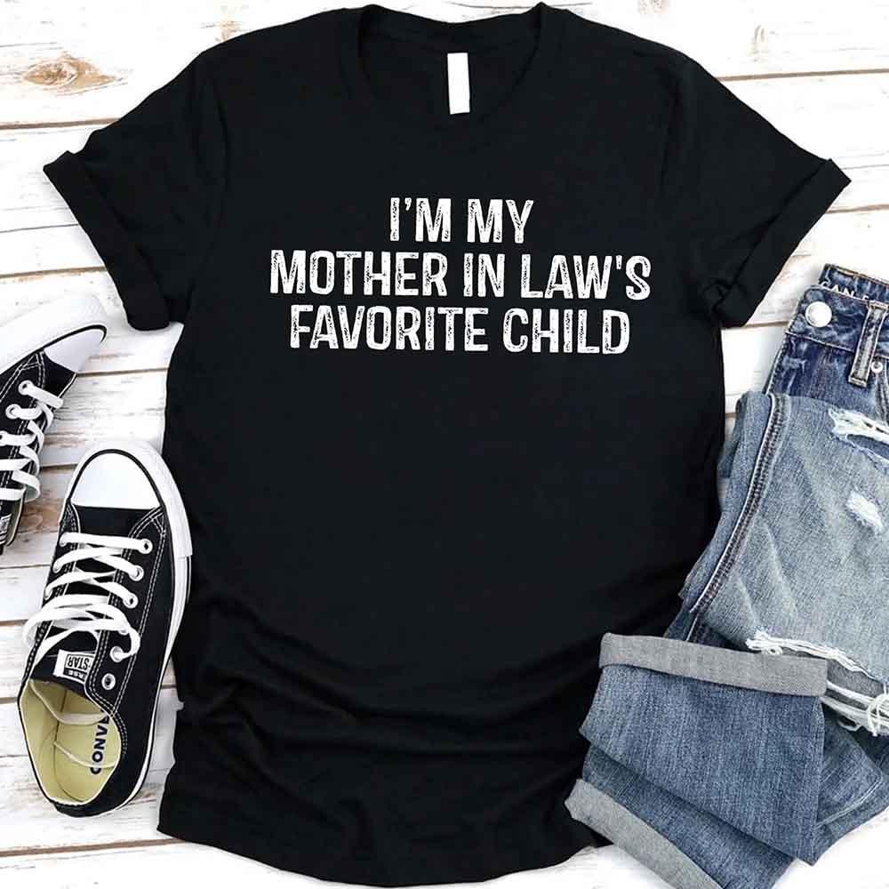 Black crew-neck T-shirt with bold text “I’M MY MOTHER IN LAW’S FAVORITE CHILD”.