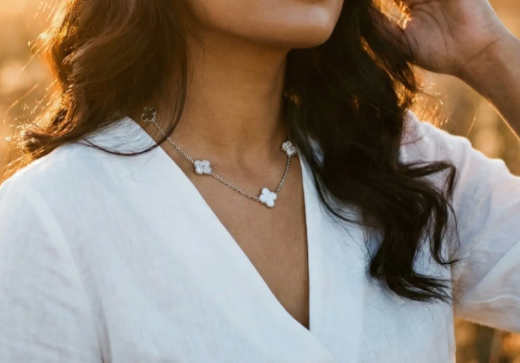 Gold-tone clover charm necklace worn close to the neck