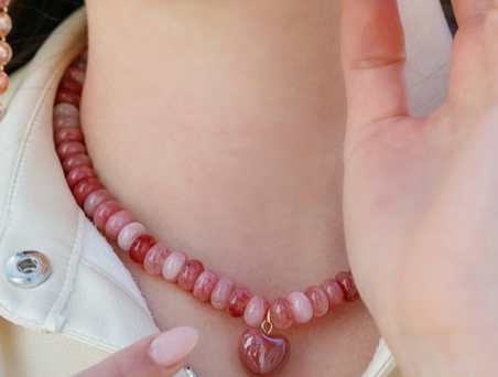 Pink beaded necklace close-up with red heart charm pendant and clasp
