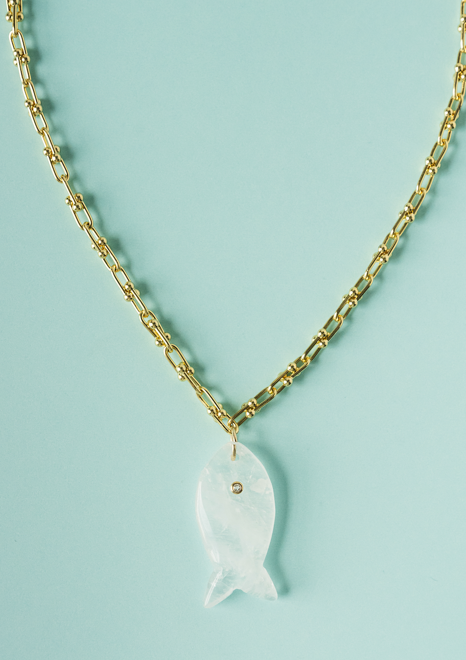 Gold fish pendant necklace with white translucent fish charm on gold chain.