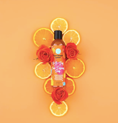Vitamin C curl defining jelly bottle with dark pump, styled amid citrus and flowers