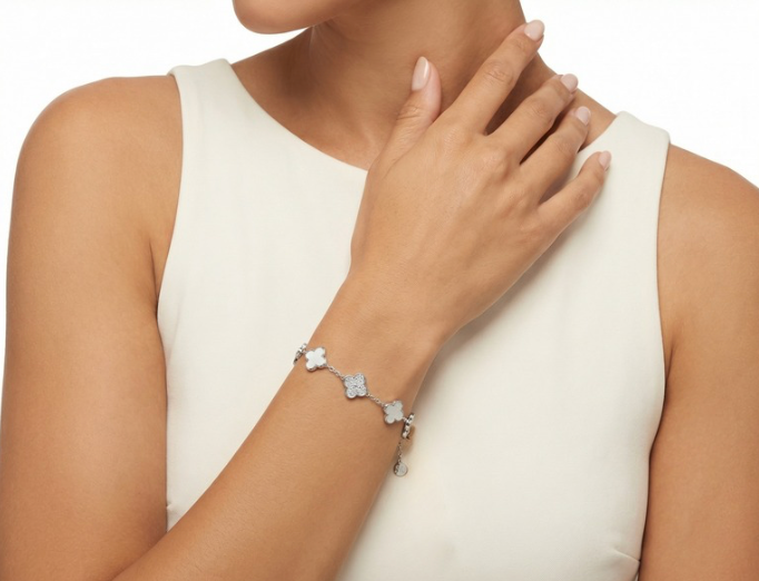 Silver-tone charm bracelet with clover and cross charms on wrist