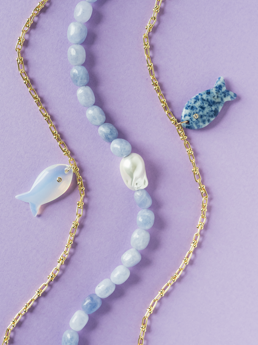 Fish pendant necklaces with white and blue charms, plus light-blue bead strand.