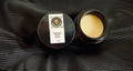 Solid scent tin with open balm cup, yellow wax center