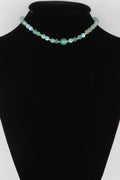 Translucent bead necklace with light blue and green beads and a central green round bead