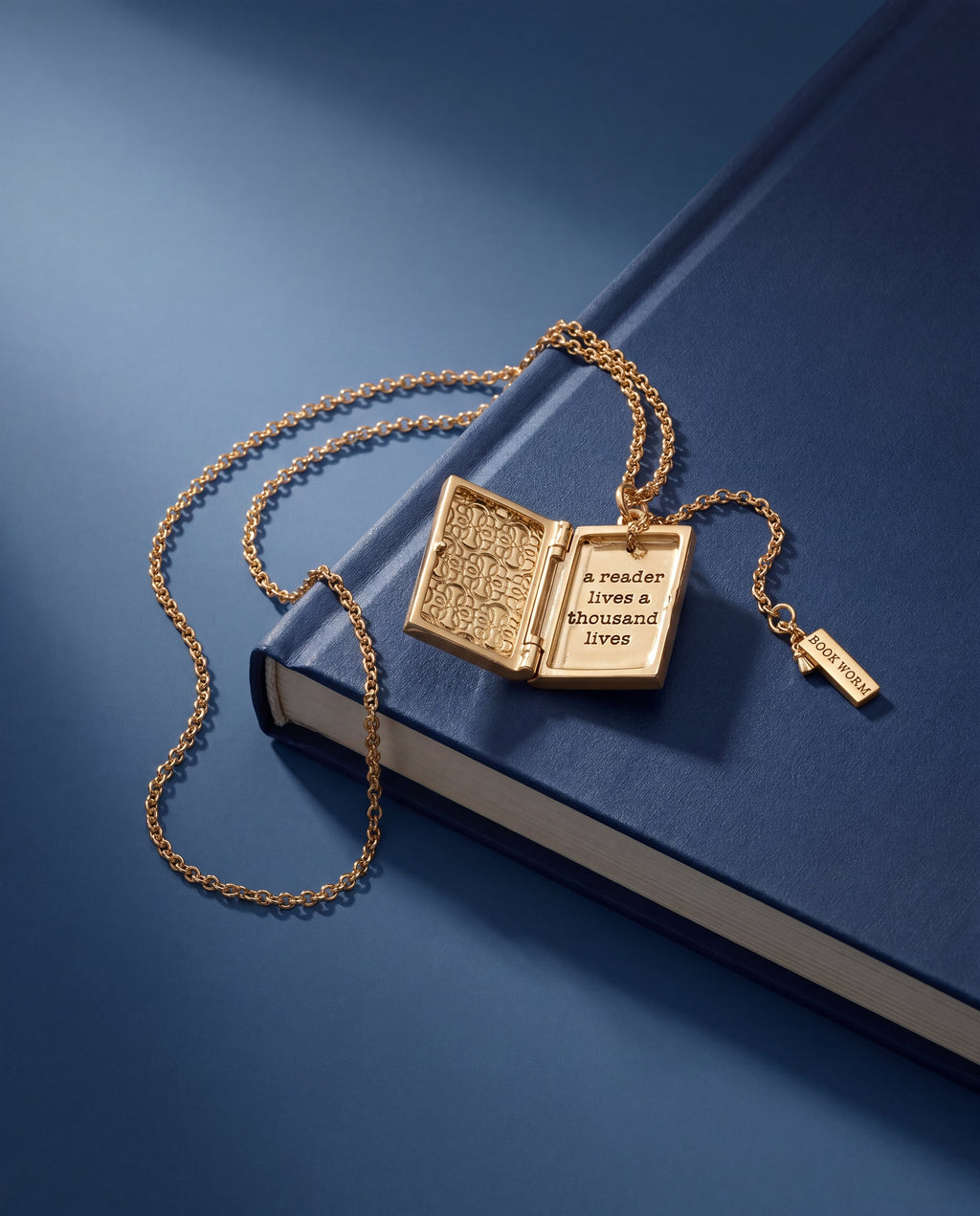 Gold locket pendant necklace with open-book face and “BOOK WORM” tag