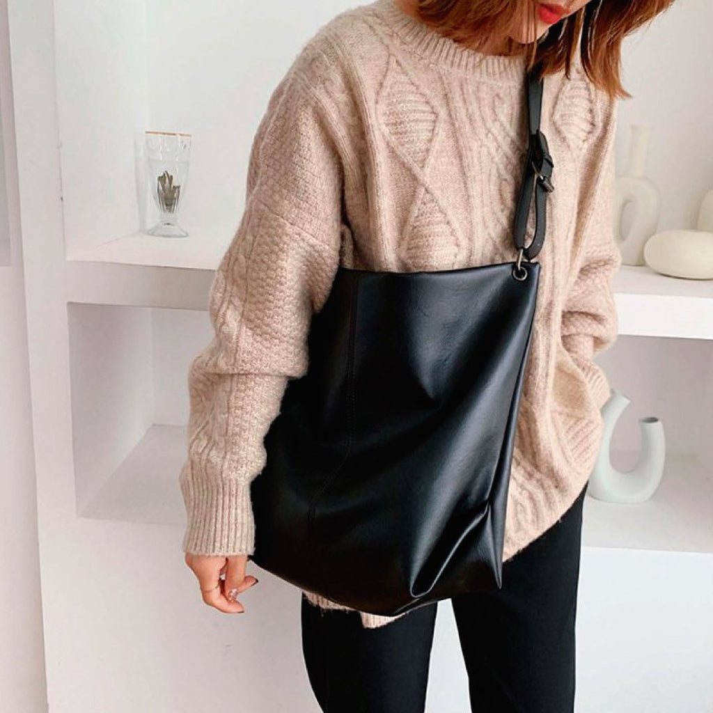 Black shoulder bag with wide strap, ring hardware, and top zipper closure