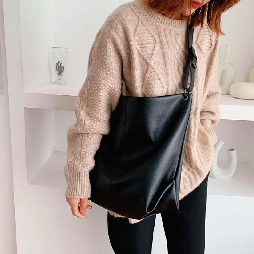 Black shoulder bag with wide strap, ring hardware, and top zipper closure