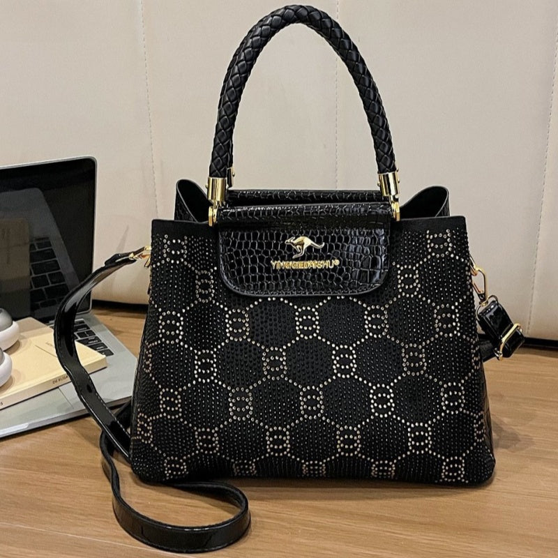 Black structured crossbody bag with top handles, front flap pocket, and gold hardware
