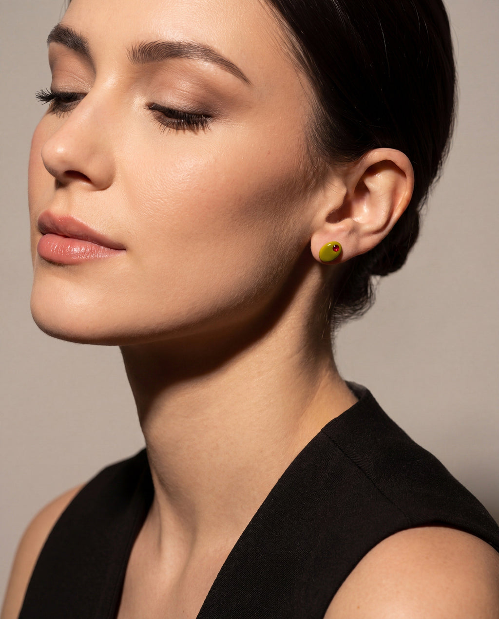 Small stud earrings with green oval and red gem on a model