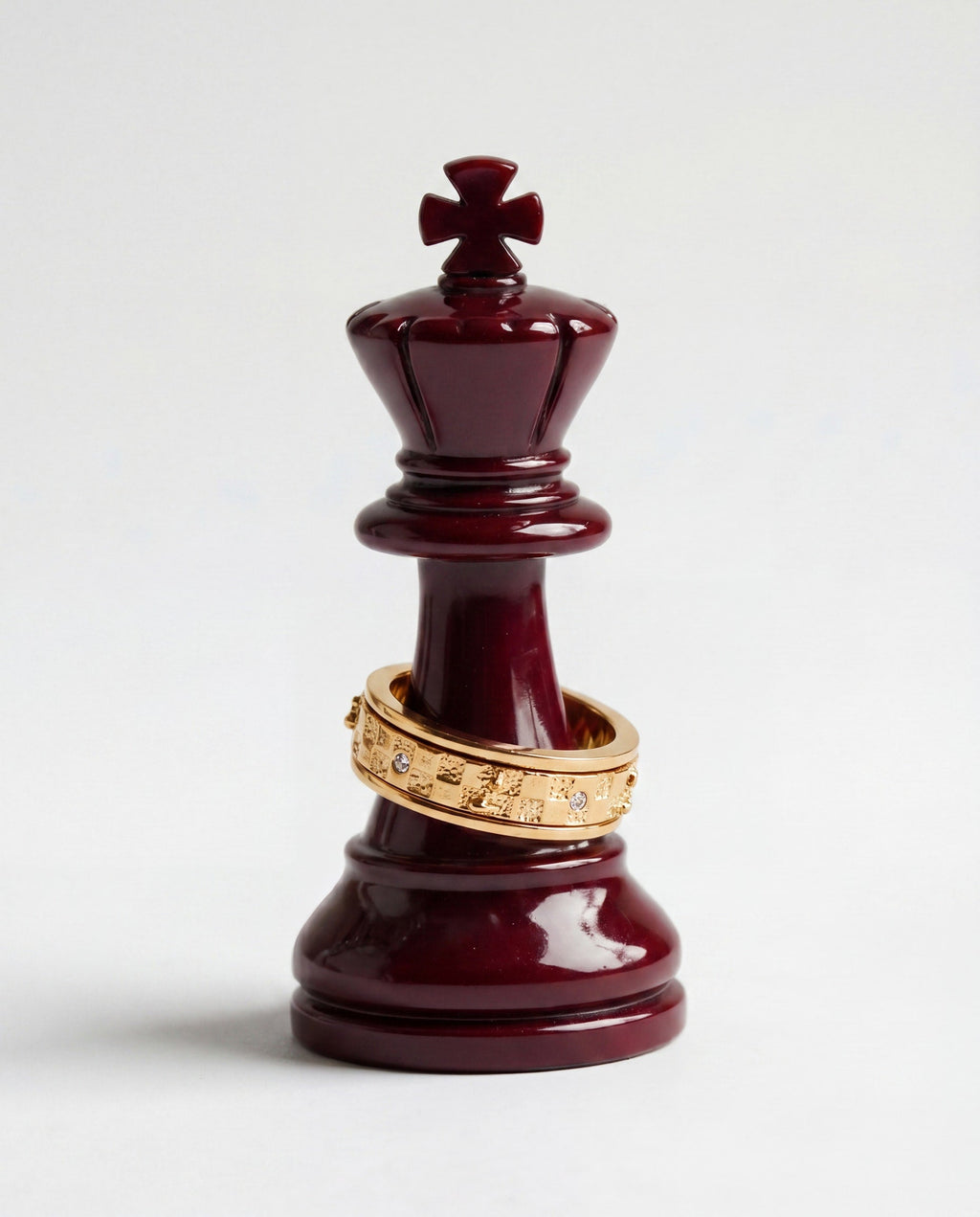 Gold-tone chess fidget ring band stacked on a red chess king piece