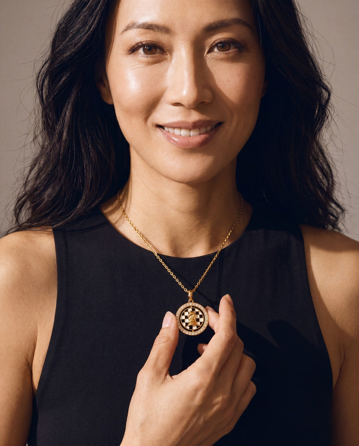 Gold chess spinner pendant necklace on model, round crystal halo and chessboard design