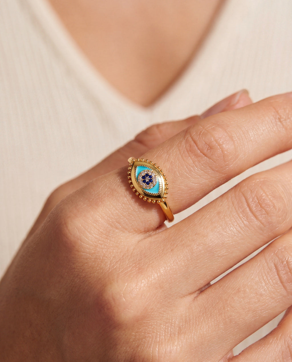 Gold evil eye ring with blue teardrop design and crystal bead halo on hand