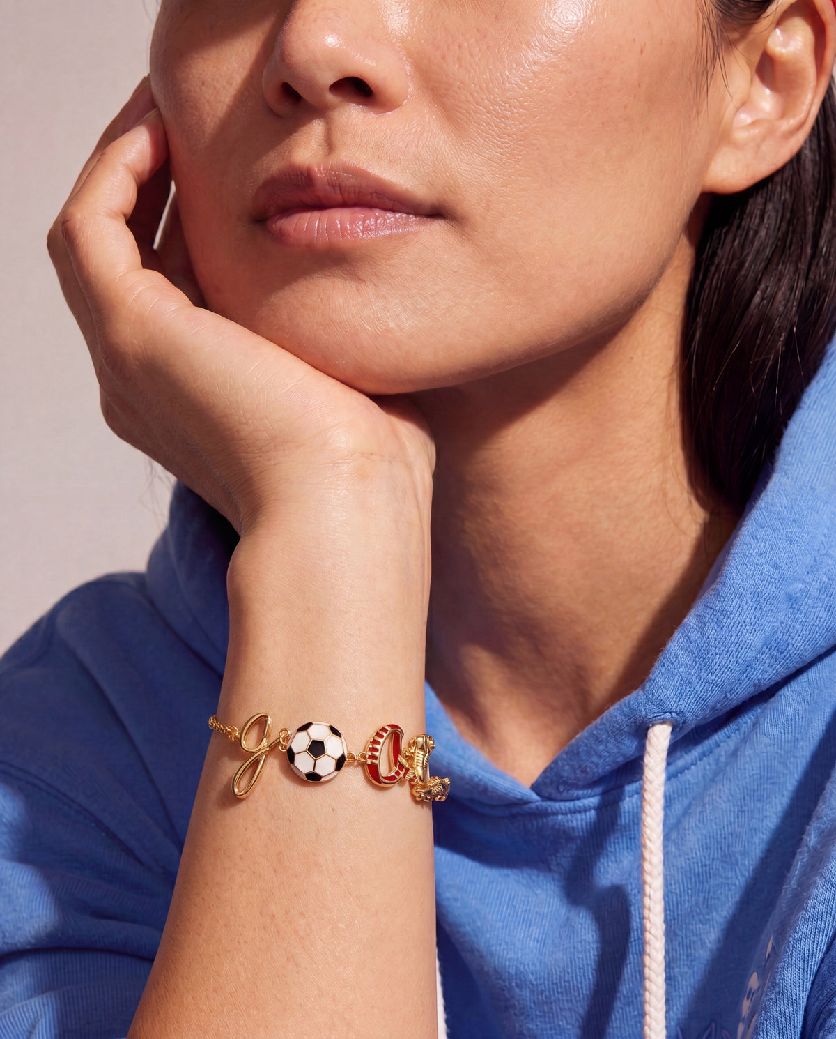 Gold soccer goal bracelet with soccer ball, red boot, and ring charms worn on wrist