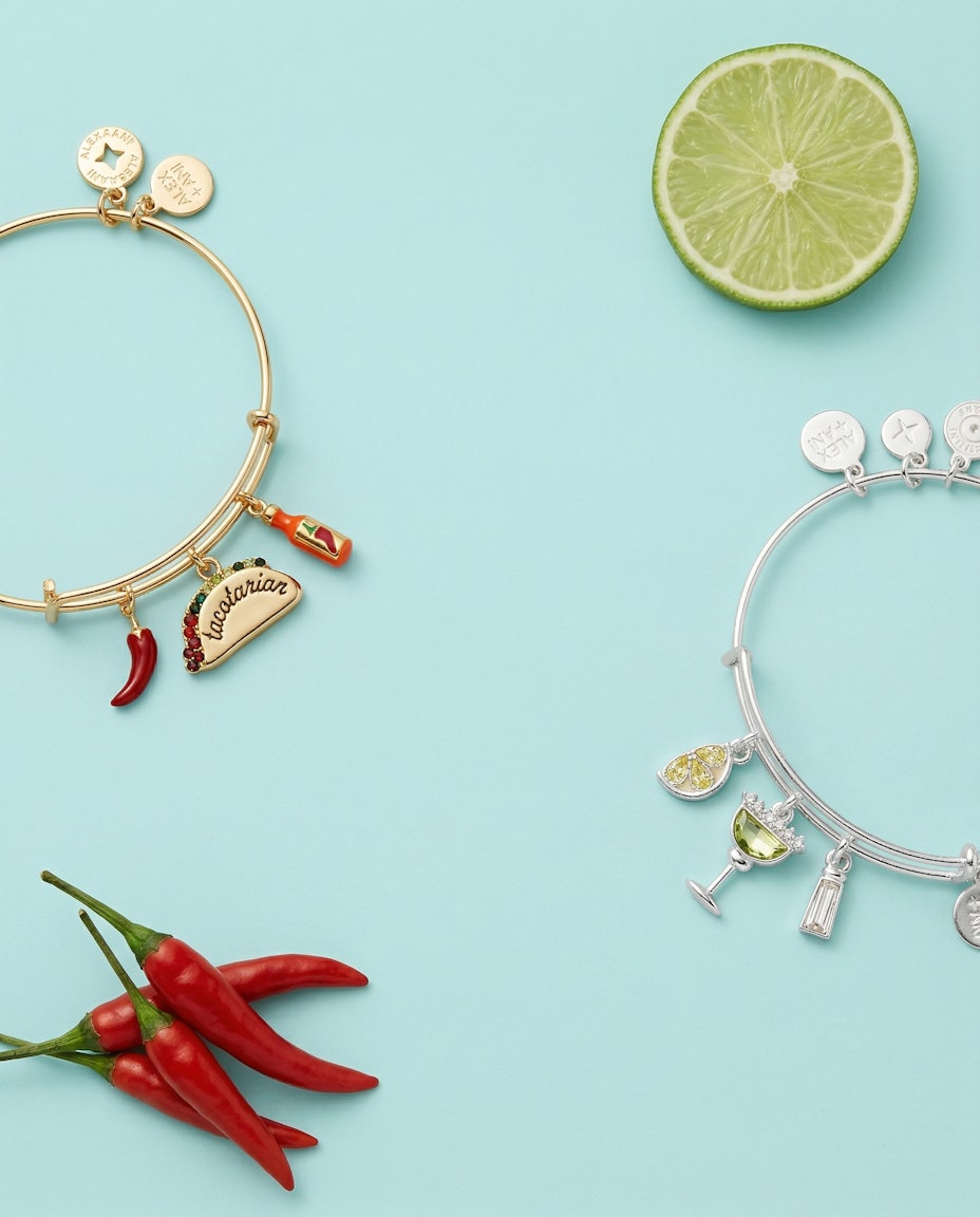 Gold bangle set with taco, chili, and bottle charms laid flat
