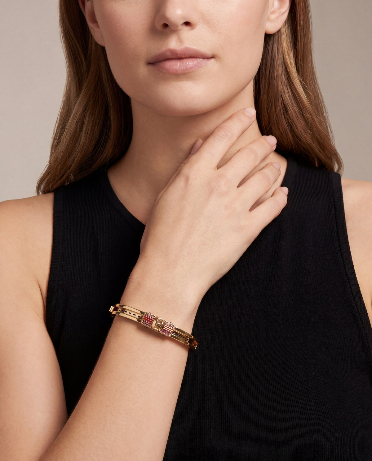 Gold-tone crystal fidget bangle on wrist against a black sleeveless top