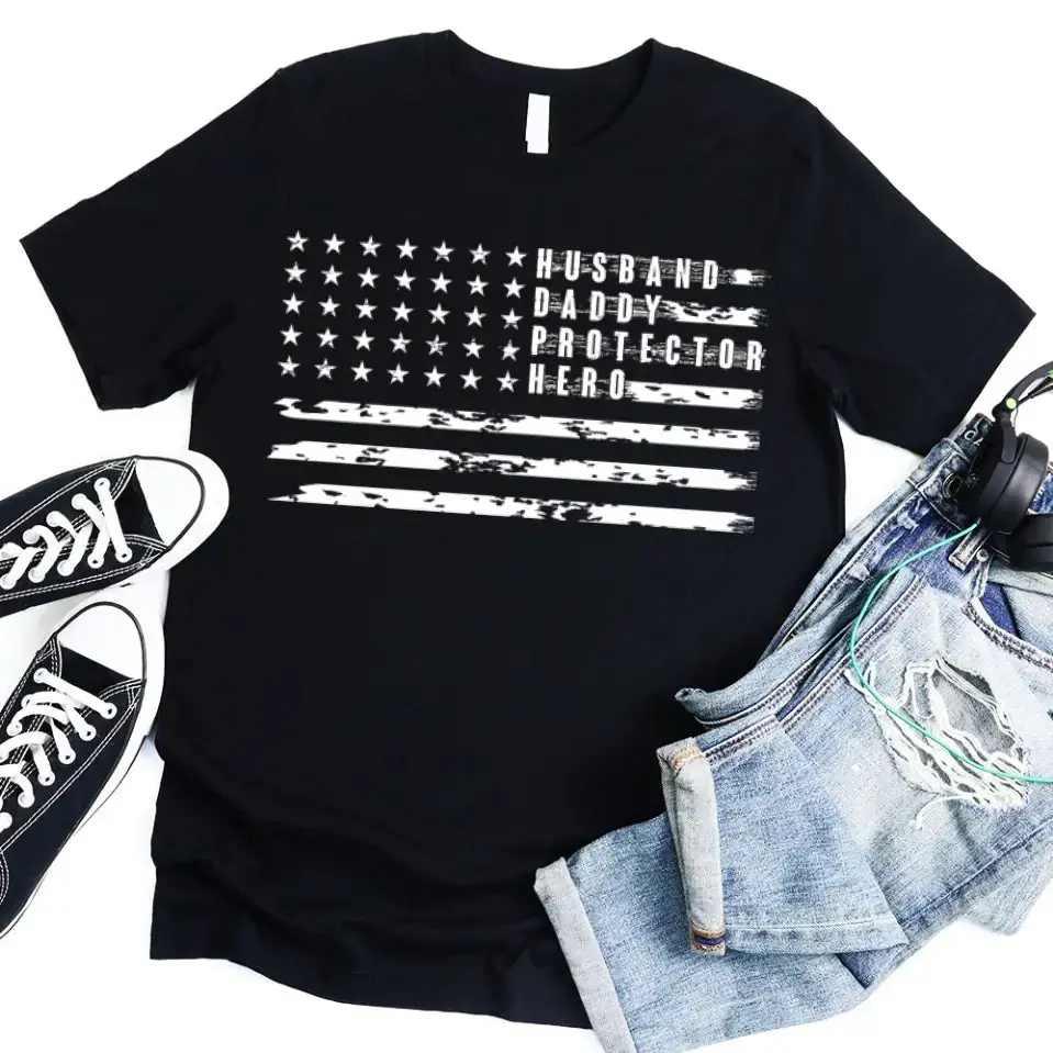 Black crewneck T-shirt with star flag stripes and 'Husband Daddy Protector Hero' print.