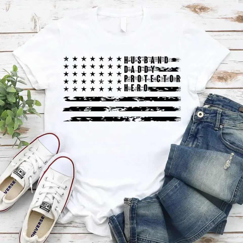 White crewneck T-shirt with star flag stripes and 'Husband Daddy Protector Hero' print.