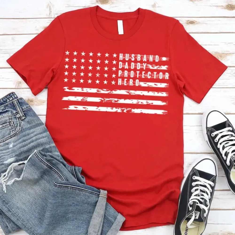 Red crewneck T-shirt with star flag stripes and 'Husband Daddy Protector Hero' print.