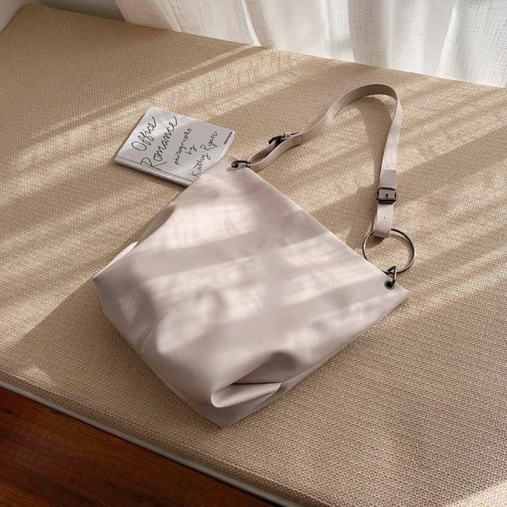 Ivory shoulder bag with adjustable strap, ring hardware, and top zipper closure