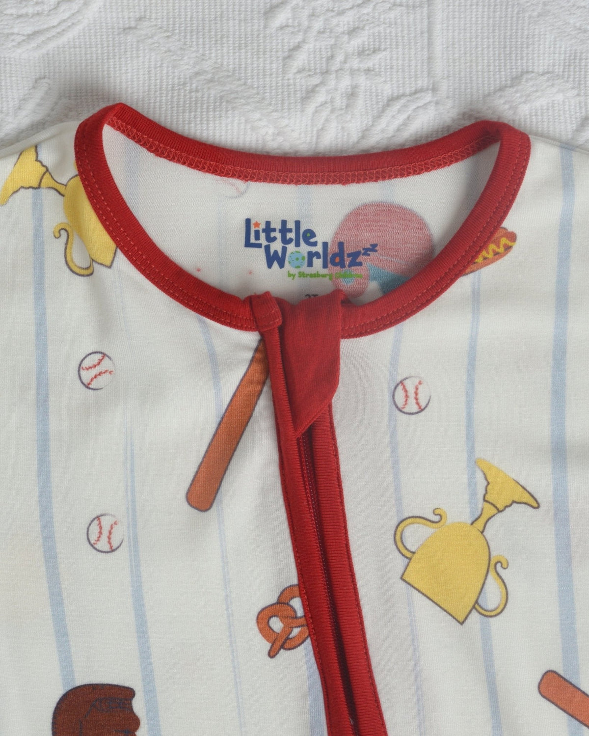 Toddler romper neckline with red tie and tag logo; baseball-themed pattern