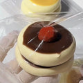 Dark brown cake-shaped squishy with glossy red berry topper