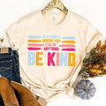 Soft cream Be Kind graphic tee with colorful “BE KIND” print and slogan above