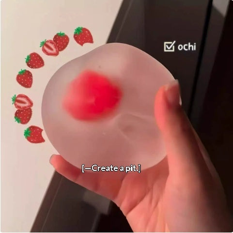 Red translucent apple-shaped stress squeeze toy, held in hand