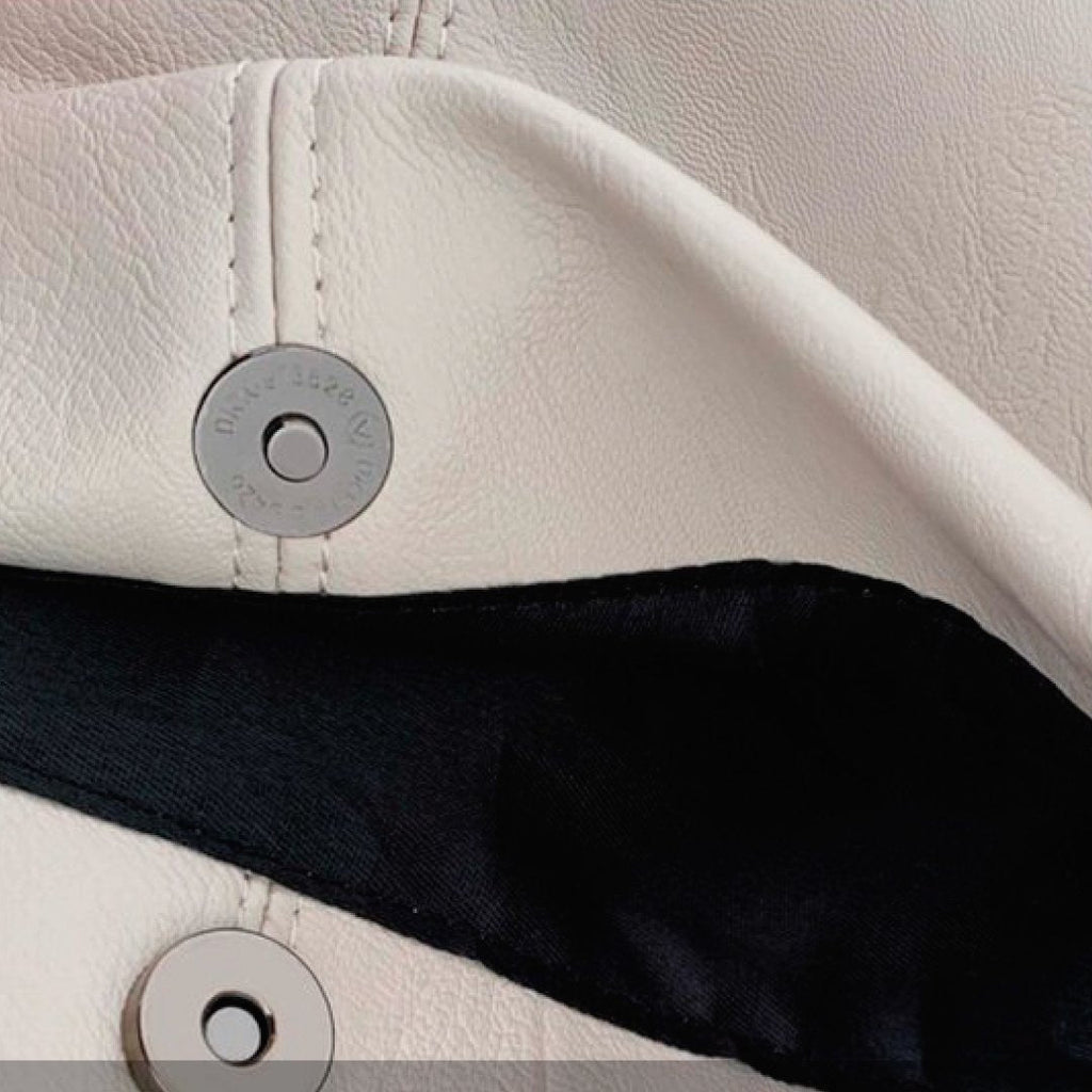 Ivory snap button panel with circular metal details on shoulder bag